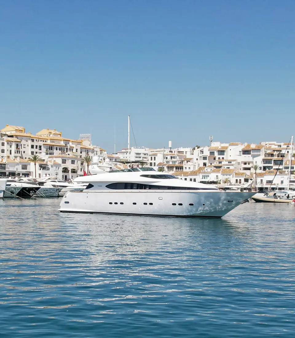 Malex at anchor in Puerto Banús, the old town behind