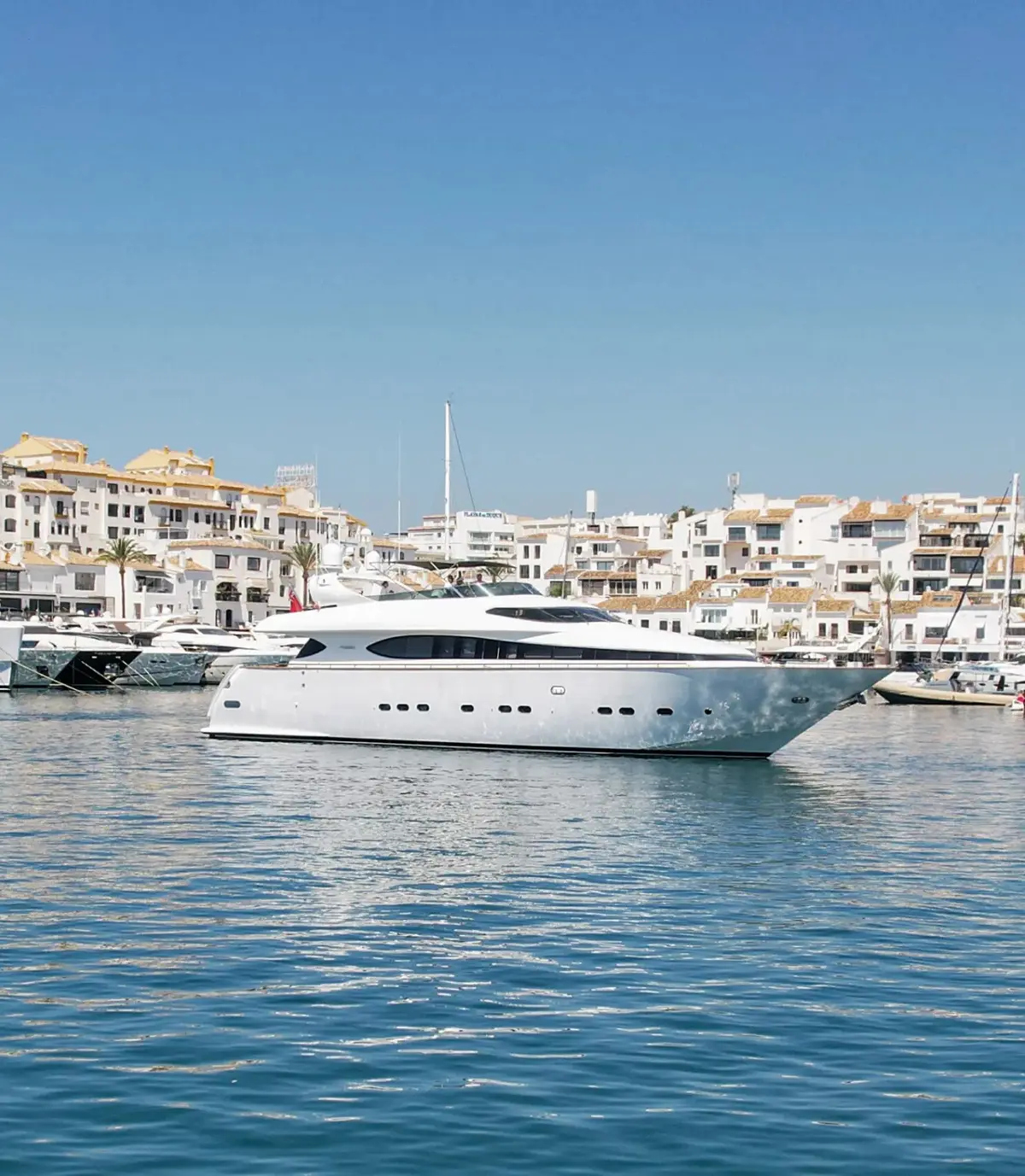 Malex at anchor in Puerto Banús, the old town behind