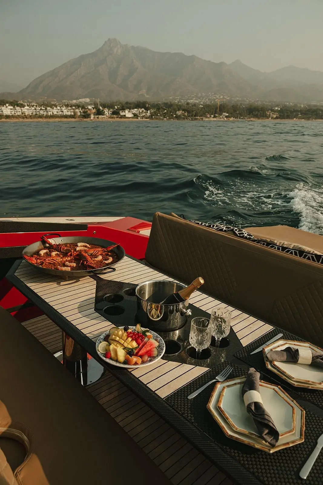 Paella, fruit and champagne on the deck table of Andalusi